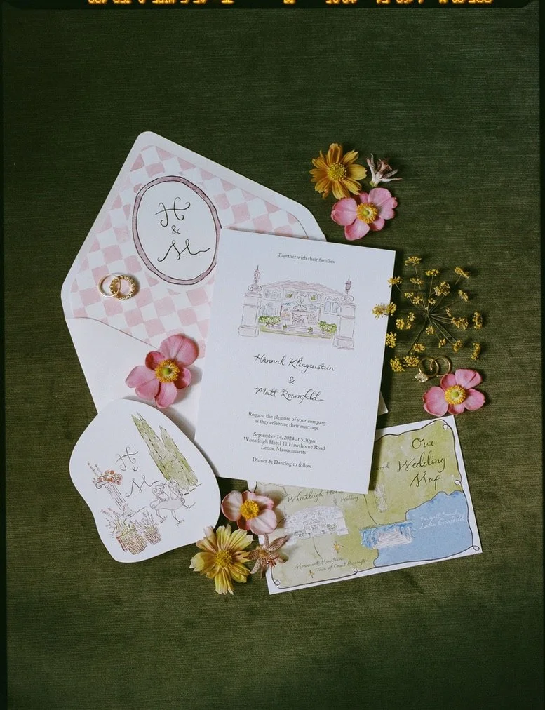 Wedding invitation with decorative flowers and wedding accessories on a dark green surface.