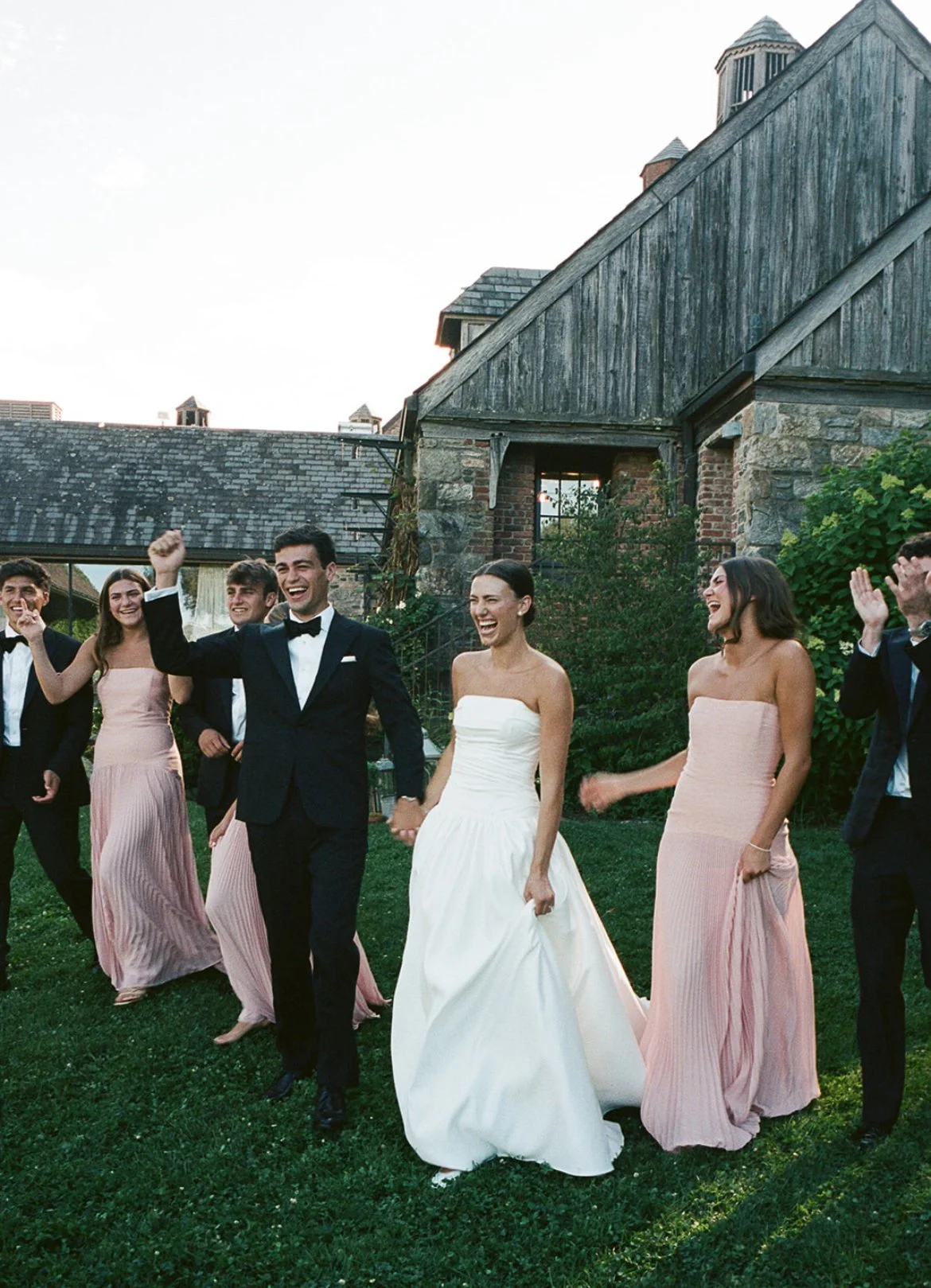 A wedding celebration with the bride and groom walking outside with friends, smiling and laughing.