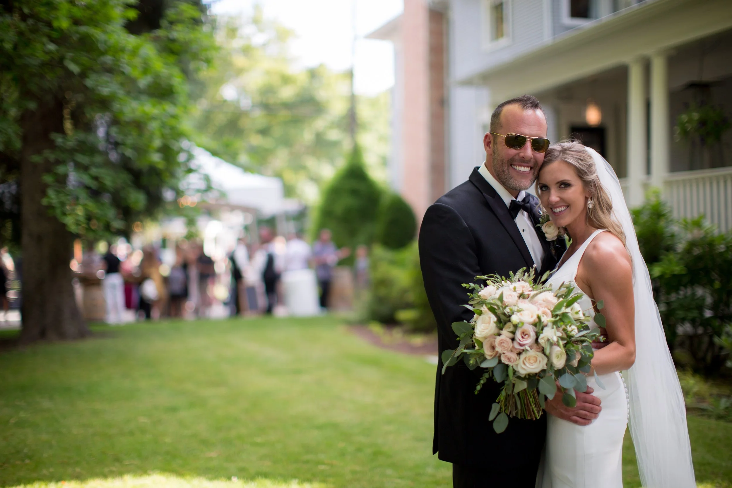 Bride and groom walking outdoors under green trees, bride wearing romantic loose curls and natural wedding makeup by Spokane and Coeur d’Alene bridal hair and makeup artist Terri Reece Studios.