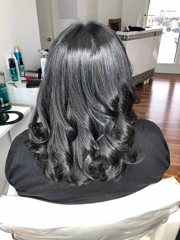 Deep, dramatic black hair color styled with soft waves