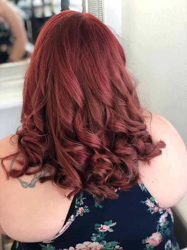 Fresh cherry hair color styled with soft curls