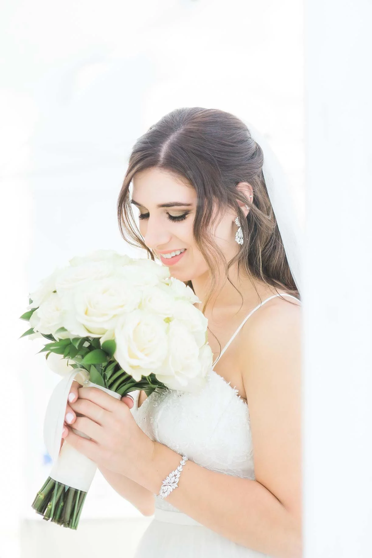 Beautiful bride on wedding day smelling white flower bouquet - Wedding hair and makeup done by Terri Reece Studios