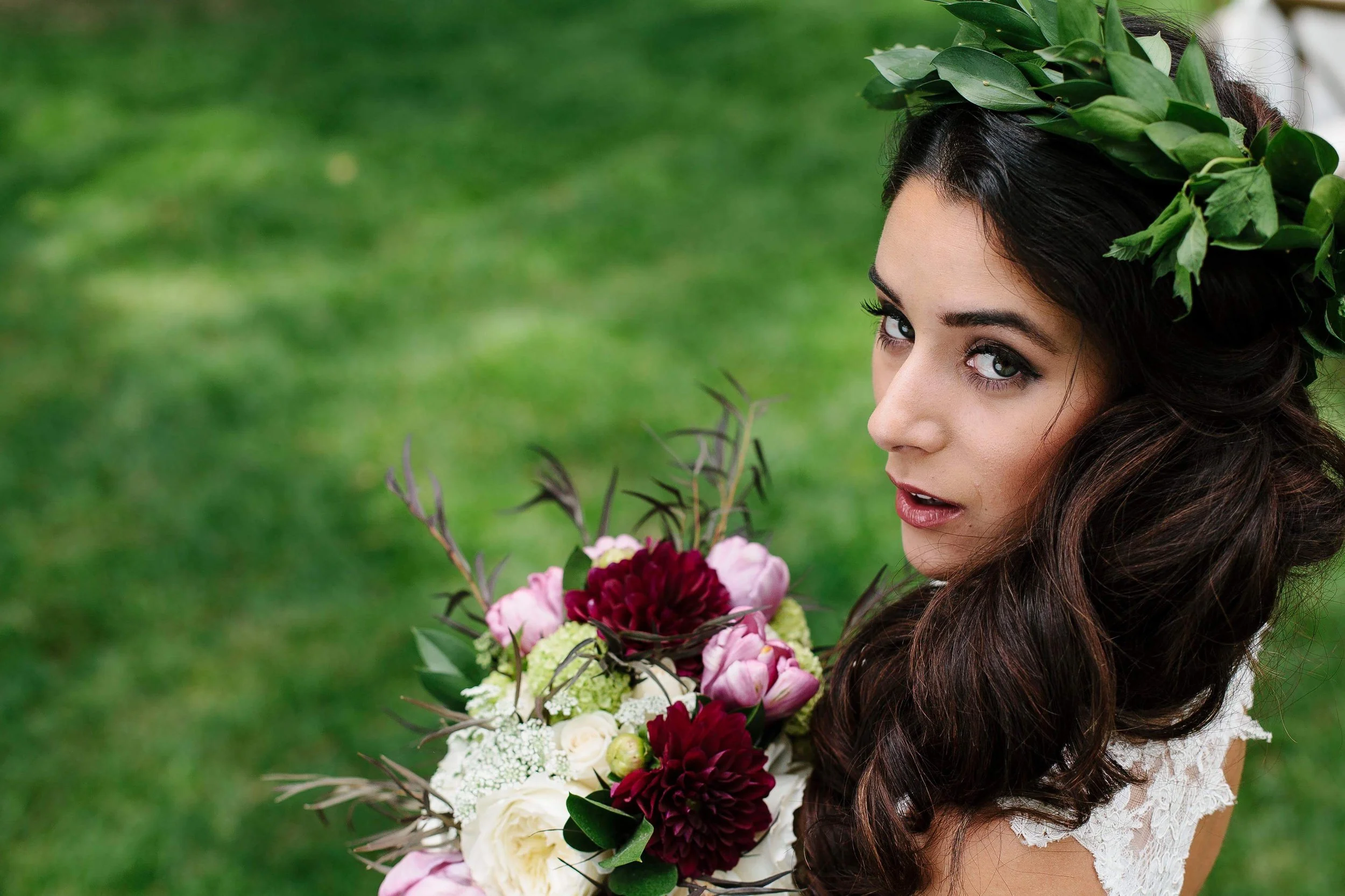 Bride with long dark waves holding a bouquet of red and white flowers, styled with soft glam wedding makeup by Spokane and Coeur d’Alene bridal hair and makeup artist Terri Reece Studios.