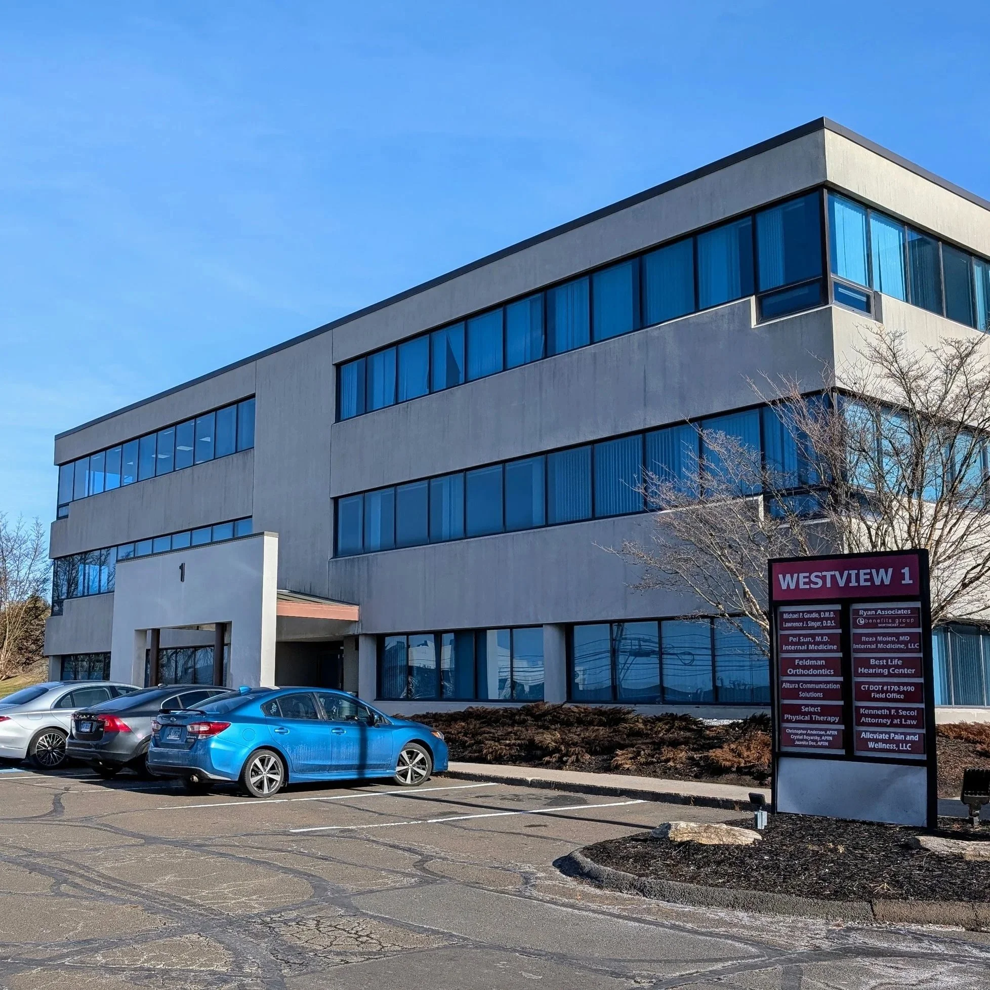 A modern, multi-story office building with large blue-tinted windows and a sign in front indicating it houses multiple medical and legal offices.  850 North Main Street Extension, Bldg-1, 2C Wallingford, CT 06492