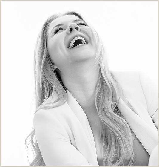woman sitting in white suit laughing in black and white