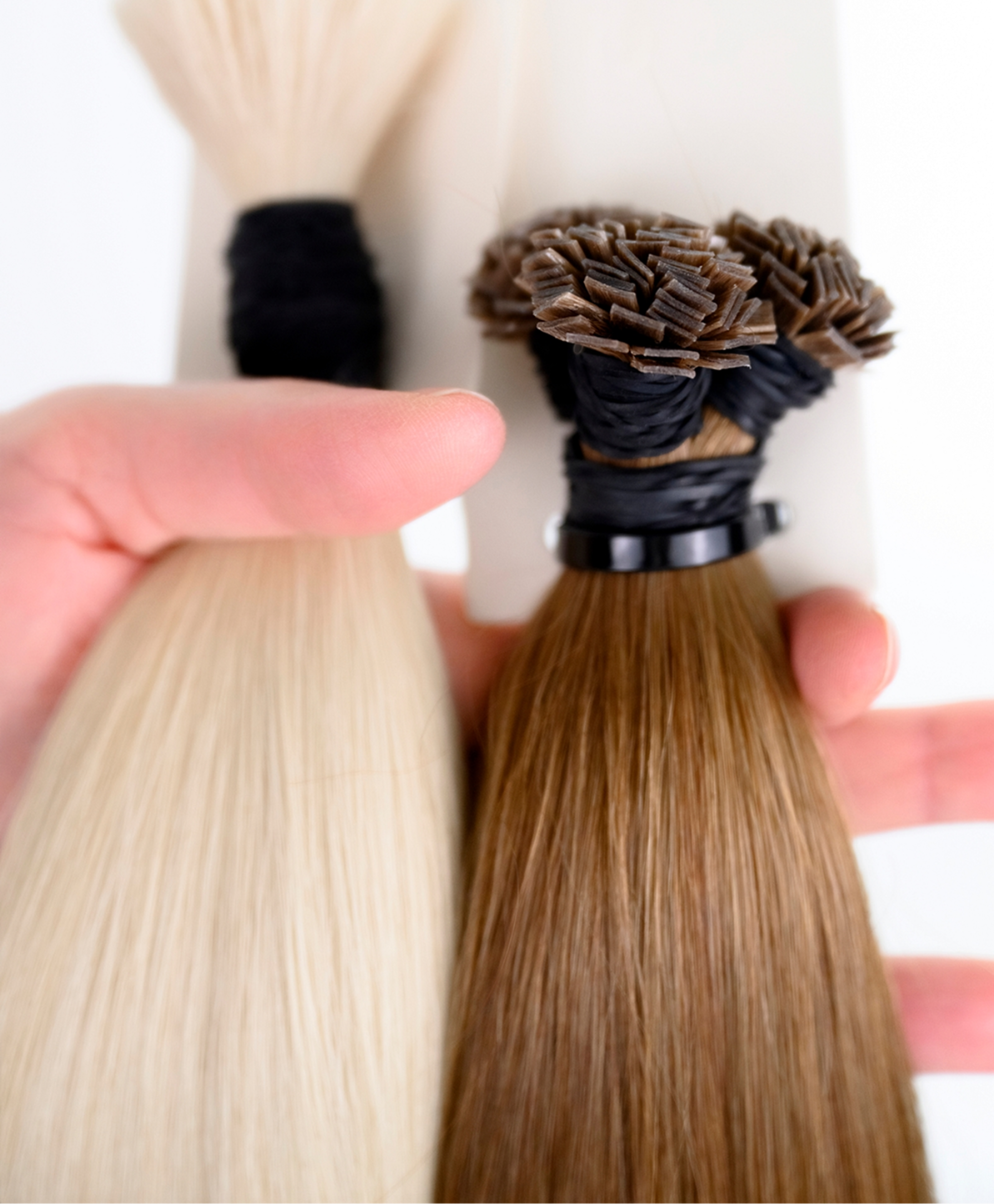 hand holding two bundles of hair extensions