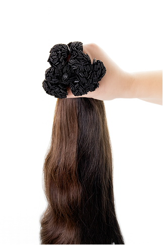 a hand holding a large bundle of dark brown hair extensions on a white background