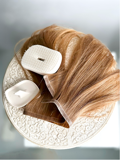 Aerial view of light brown hair extensions on a table with a hair brush