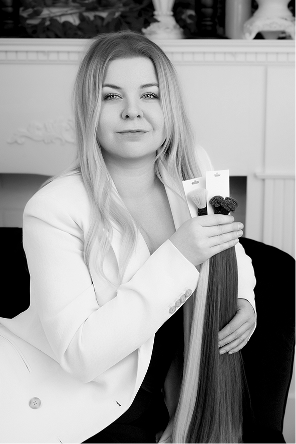 woman sitting in white suit smiling with blonde hair