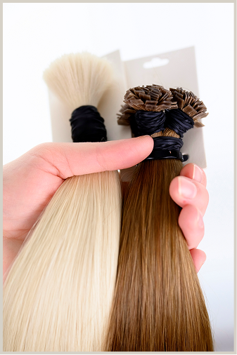 a woman holding a brunette and blonde bundle of hair extensions