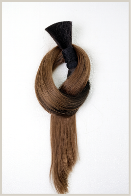 a bundle of brunette hair extensions tied in a knot displayed on a white background