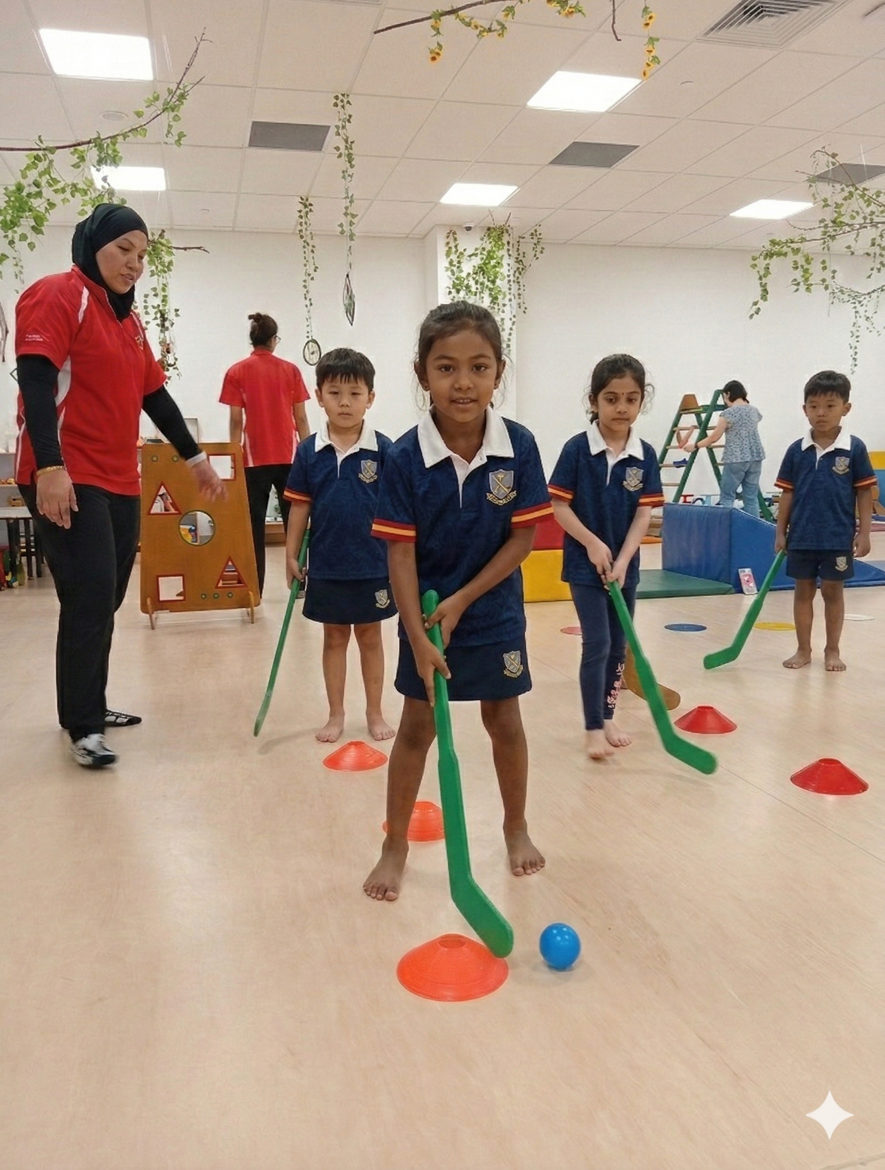 Children in blue uniforms playing indoor mini hockey game with a coach or instructor supervising.