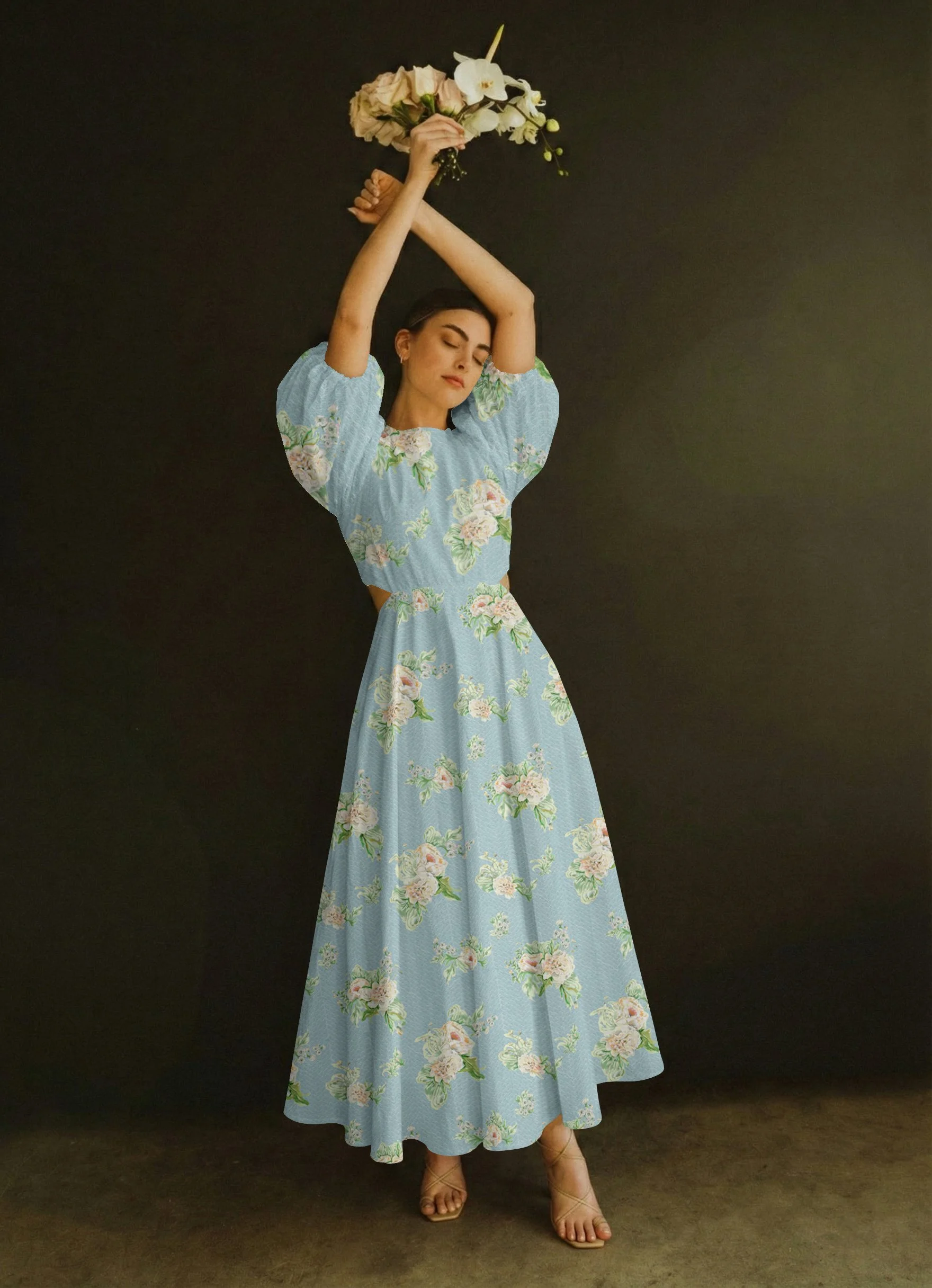 A woman in a blue floral dress holding a bouquet of white flowers above her head while standing against a dark background.