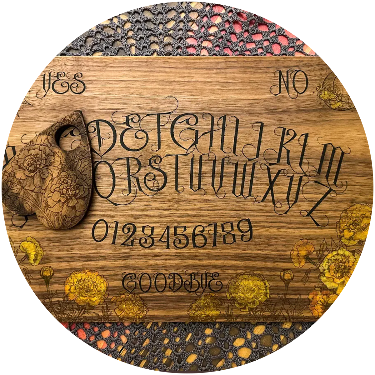 hand-painted custom engraved walnut spirit board with black letters and yellow and orange marigolds rests on a black lace tablecloth