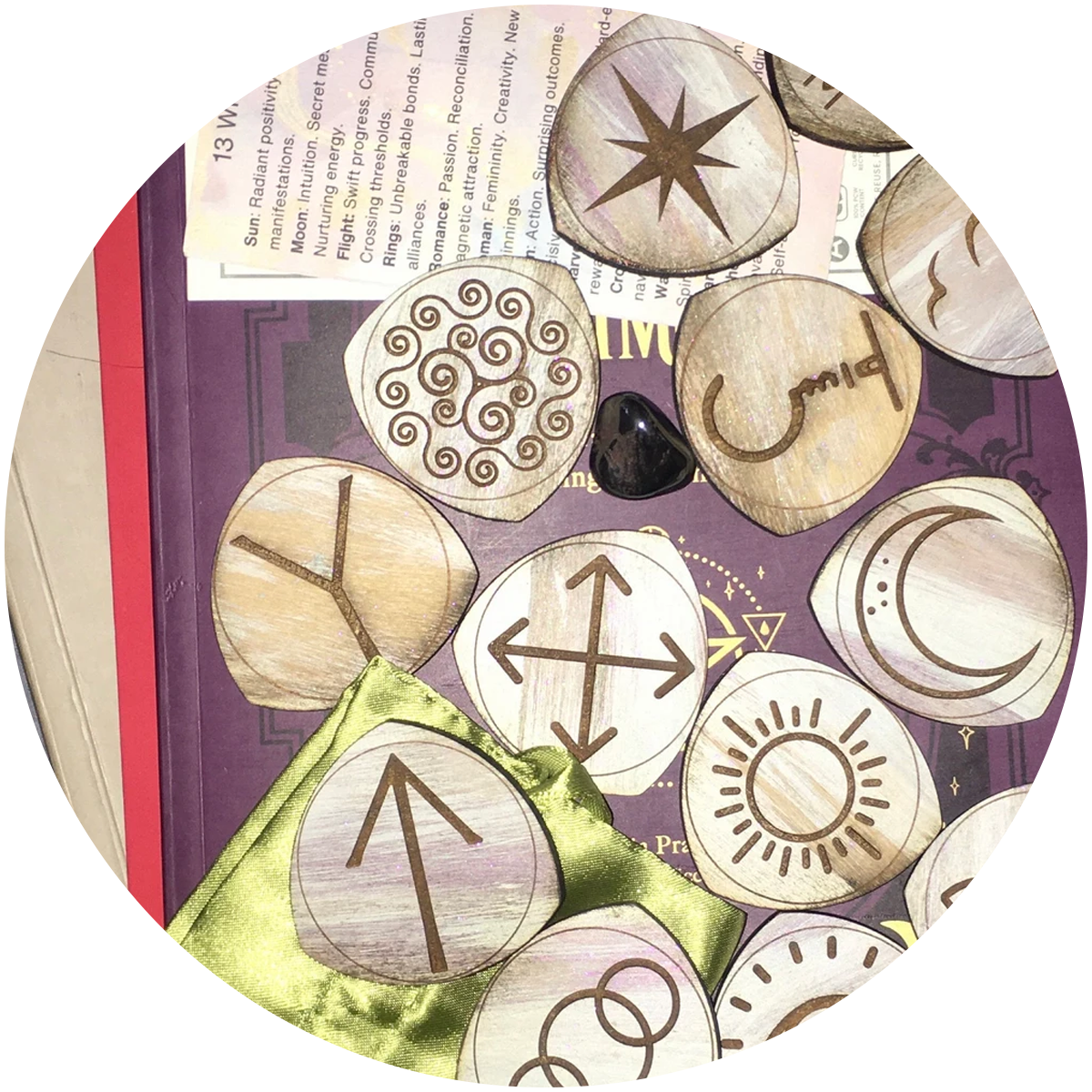 handmade glow in the dark engraved wood runes with a satin bag and interpretation sheet rest on a stack of books