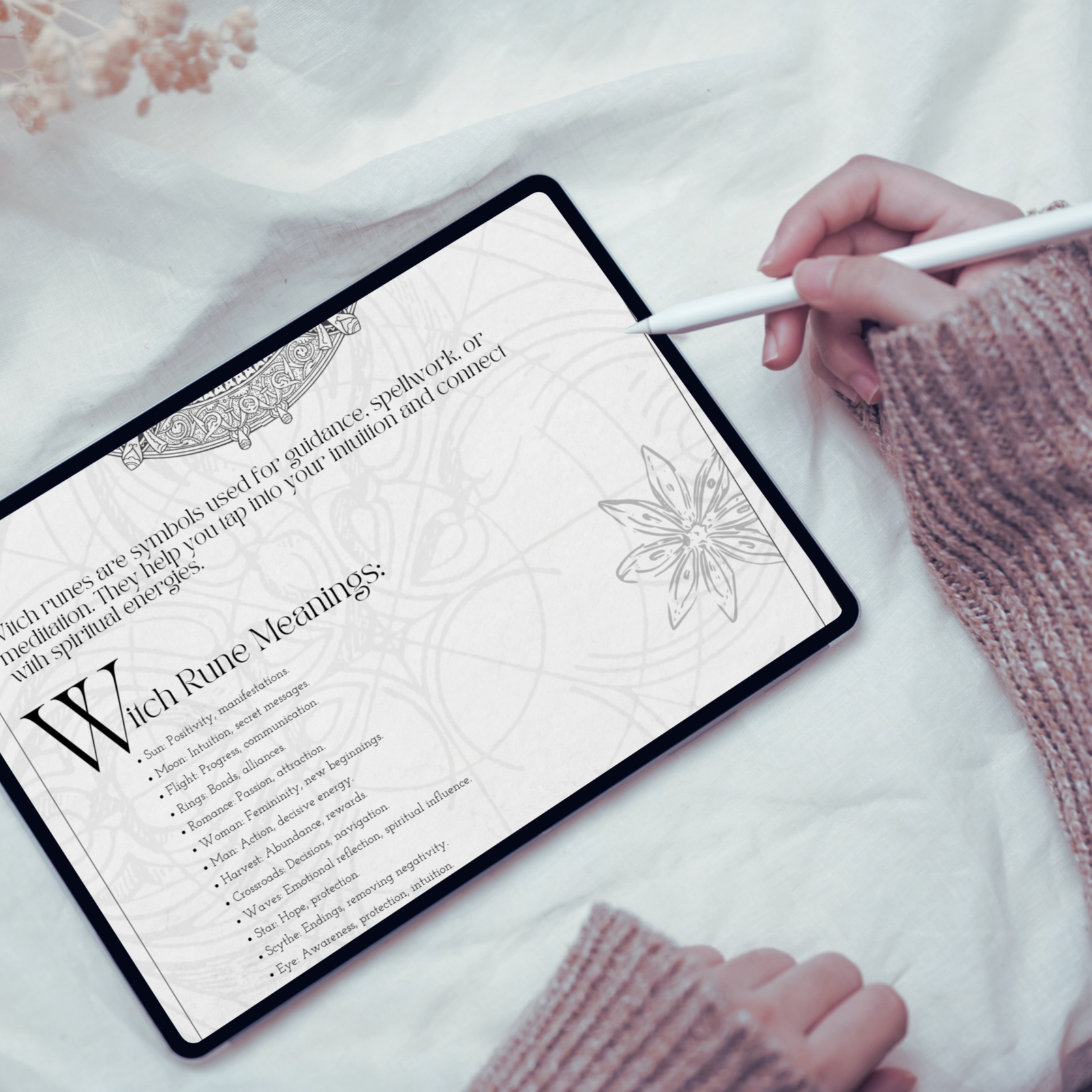 A digital tablet displays a guide to witch runes digital grimoire page. Hands with a stylus rest next to the tablet displaying customizable digital grimoire download on screen..