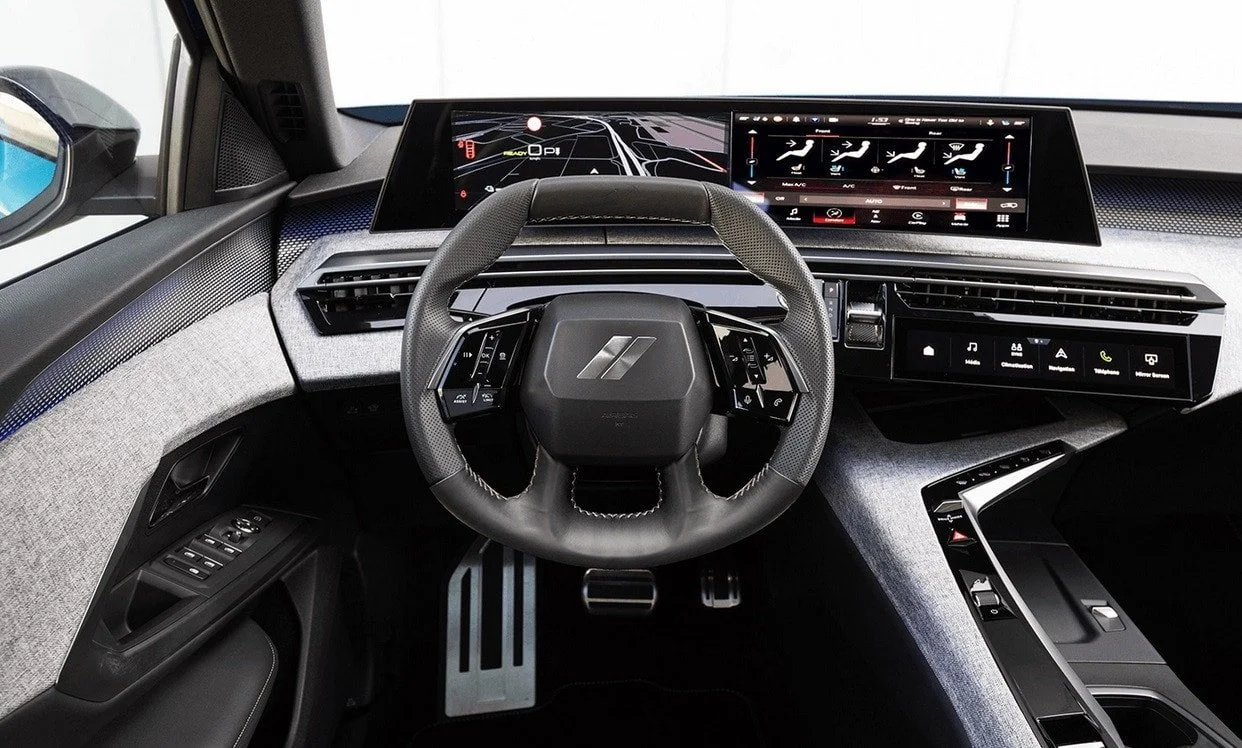 Interior of a modern car showing a digital dashboard display, steering wheel with controls, and center console with touch controls.