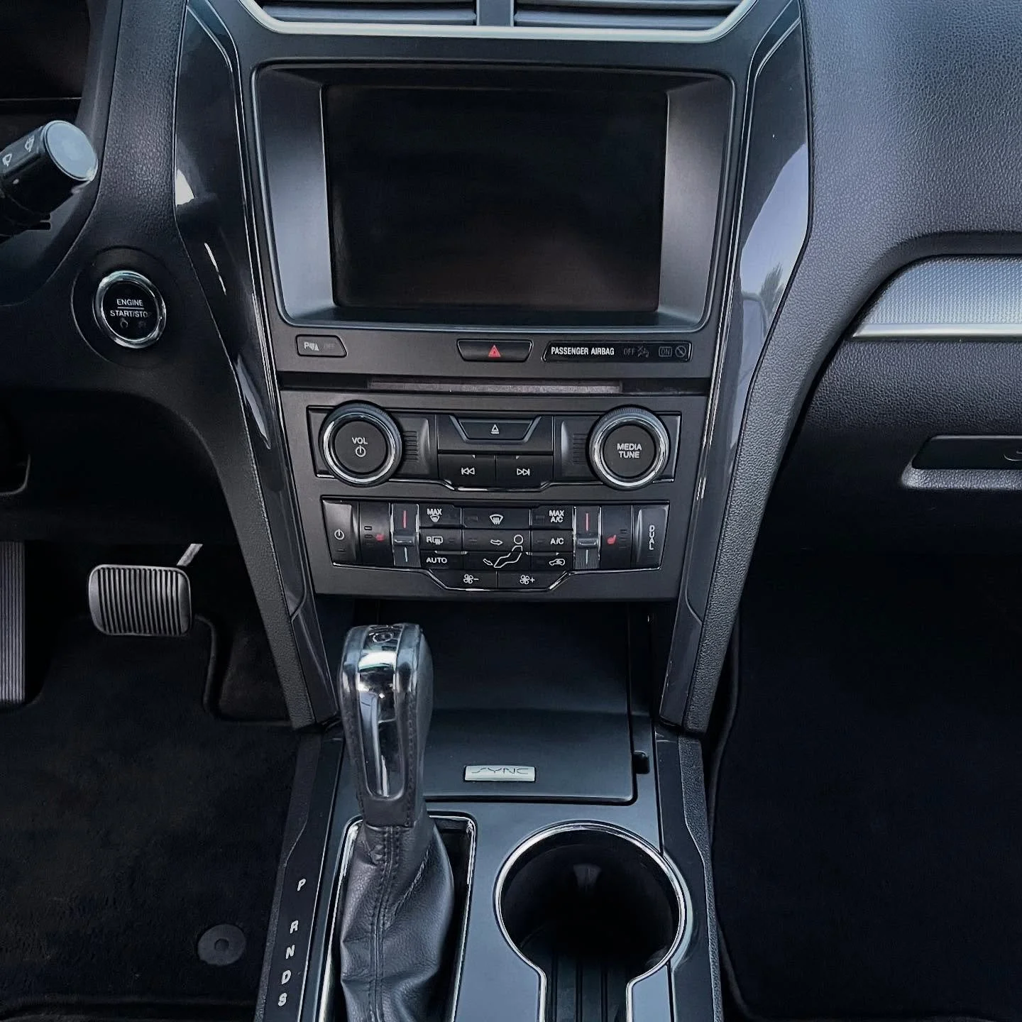 Center console of a car interior with a gear shift, cup holder, and dashboard controls.