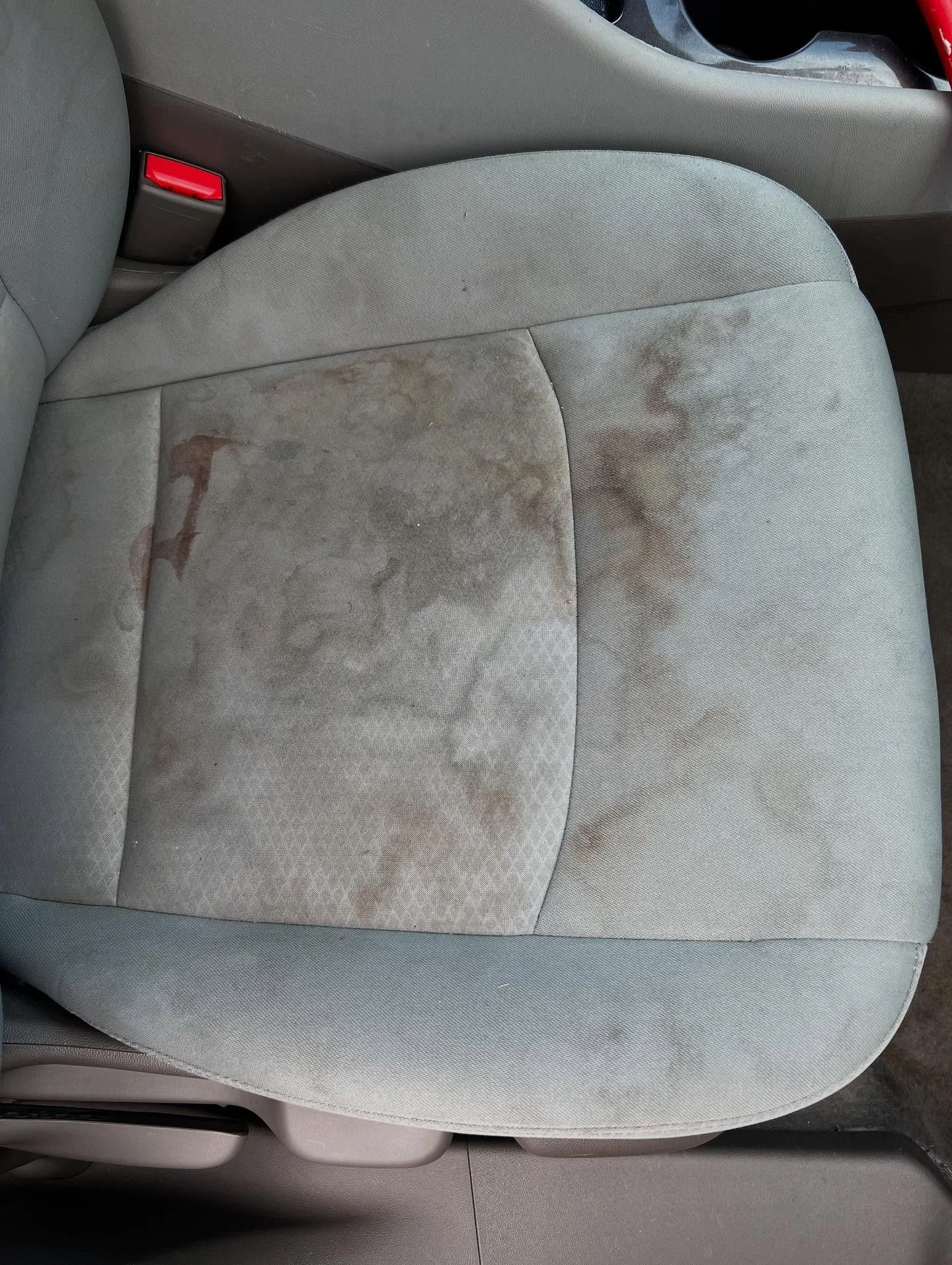 A car seat with noticeable dirt and stains on the light gray fabric.