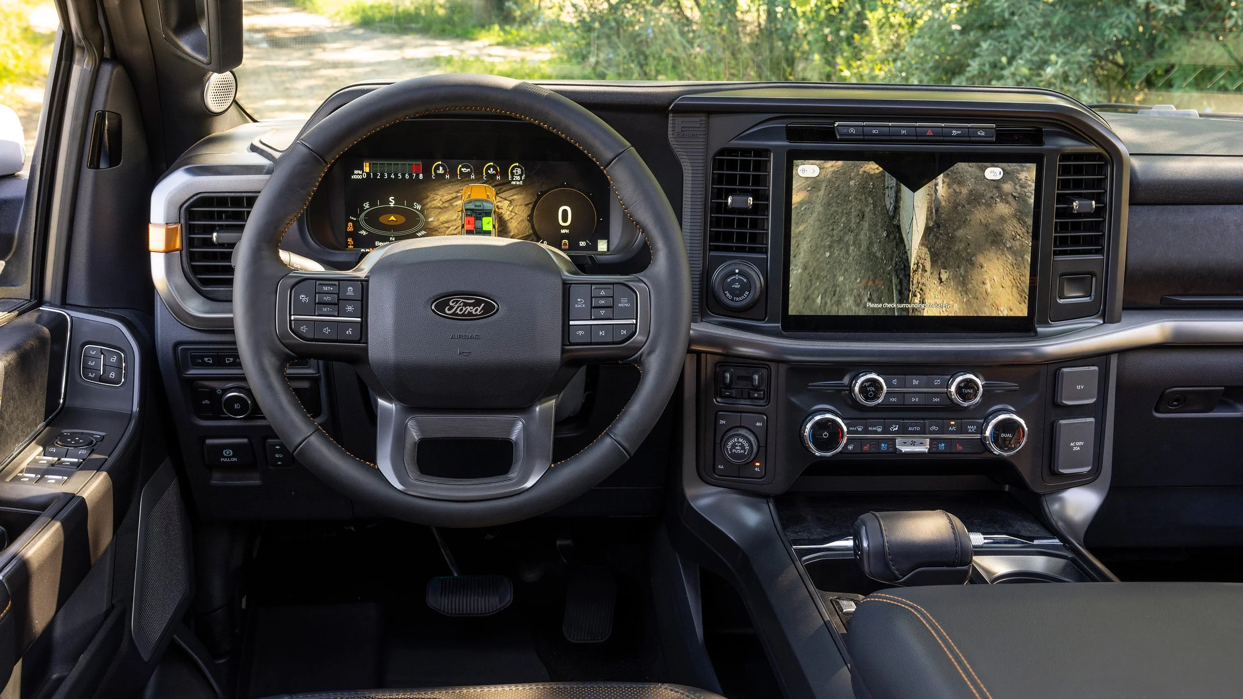 The interior of a Ford vehicle showing the steering wheel, digital dashboard, large central touchscreen with a backup camera view, and various control buttons.