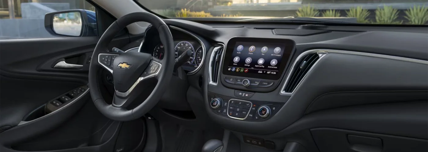 Interior of a Chevrolet car showing the dashboard, steering wheel with Chevrolet logo, and center console with digital display.