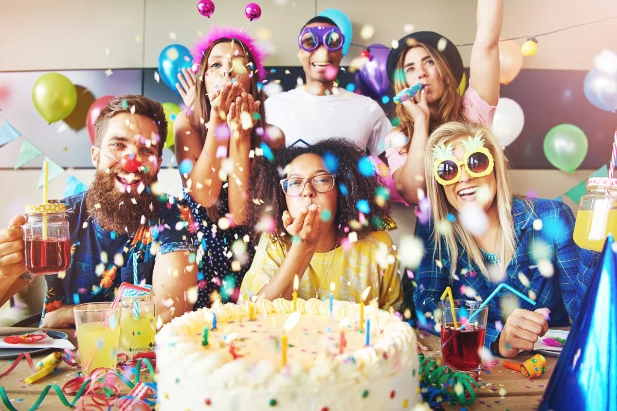 Group of friends celebrating a birthday with cake and confetti, capturing joyful moments ideal for personalised video gifts
