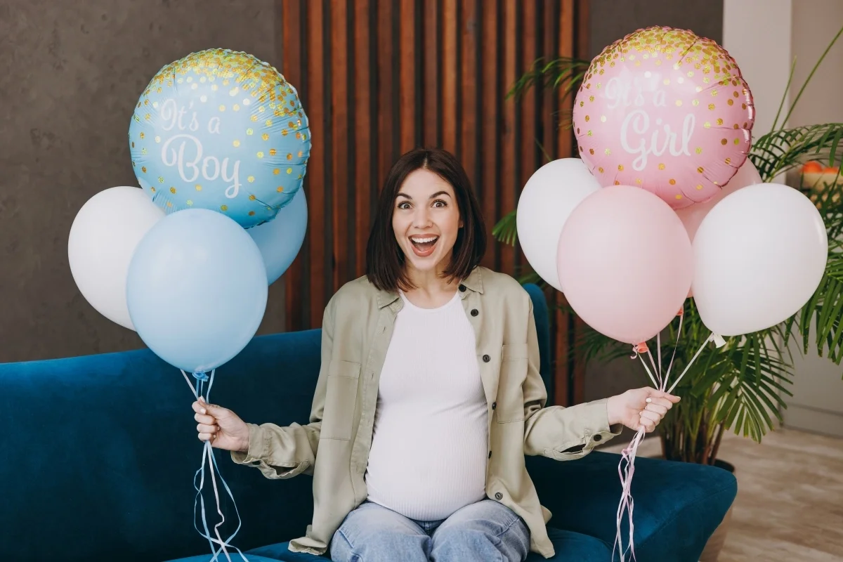 Woman holding pink and blue balloons at a baby gender reveal party, celebrating pregnancy announcement and joyful anticipation