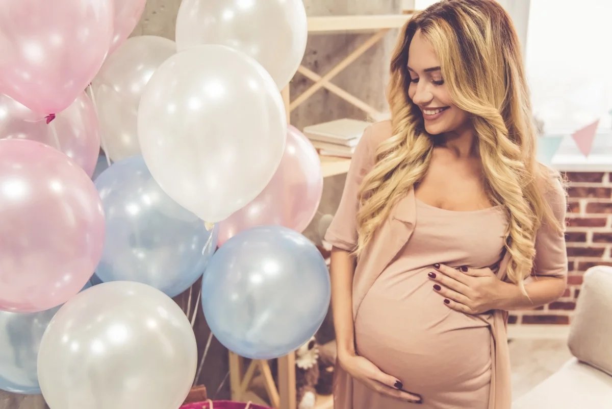 Pregnant woman at baby shower with pastel balloons, celebrating a special milestone moment perfect for personalised video gifts