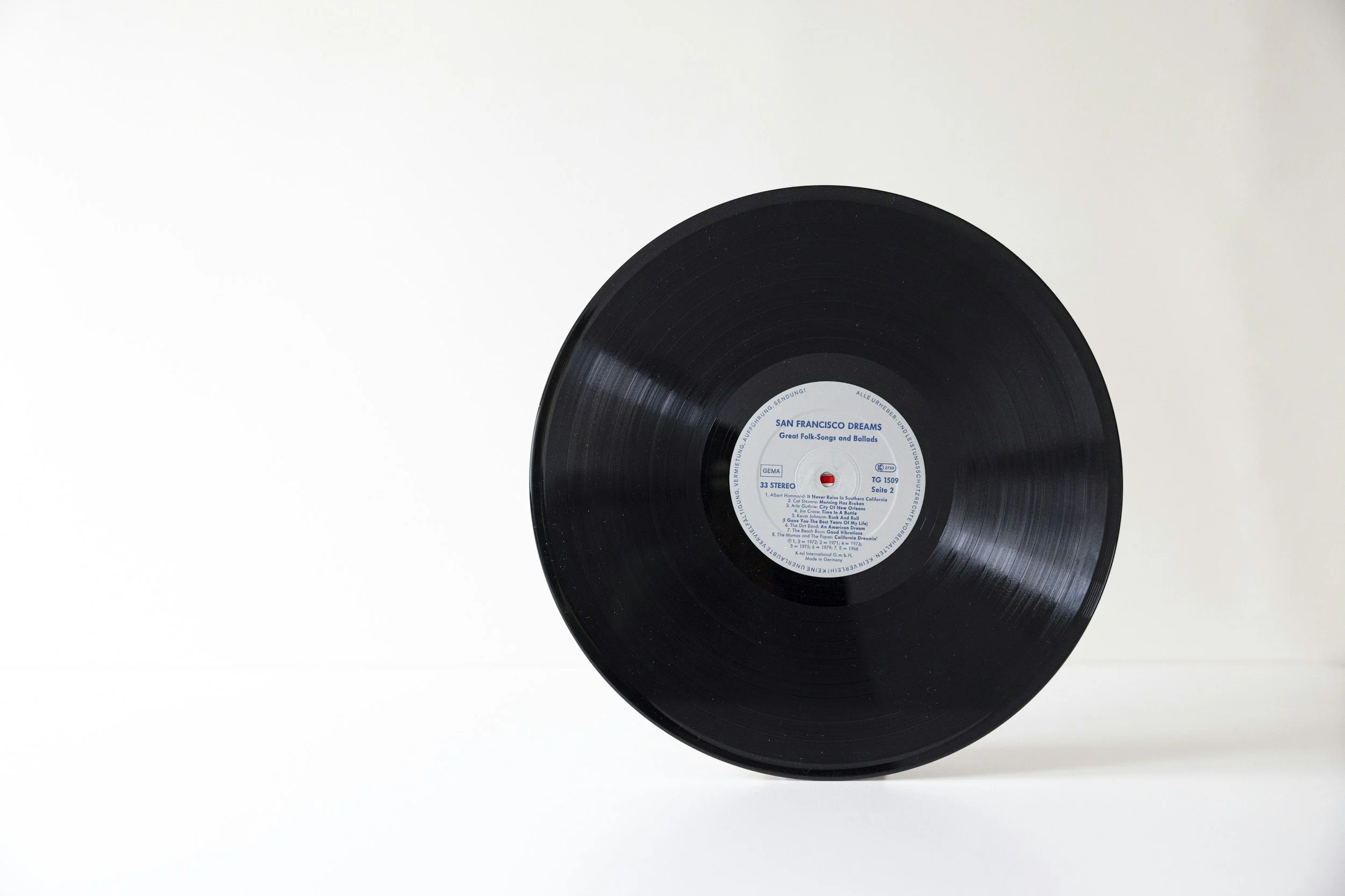 A black vinyl record with a blue and white label in the center, resting on a white surface with a plain white background.