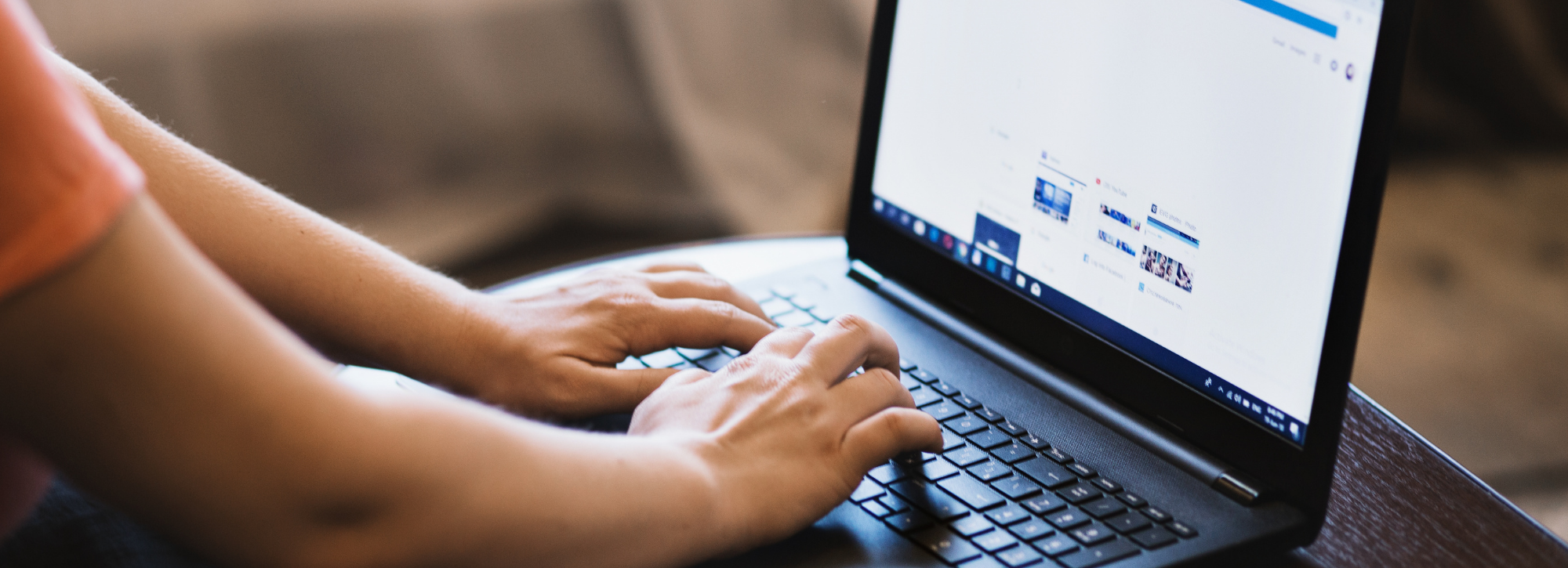 Person using a laptop on a wooden surface, with a Facebook page visible on the screen.