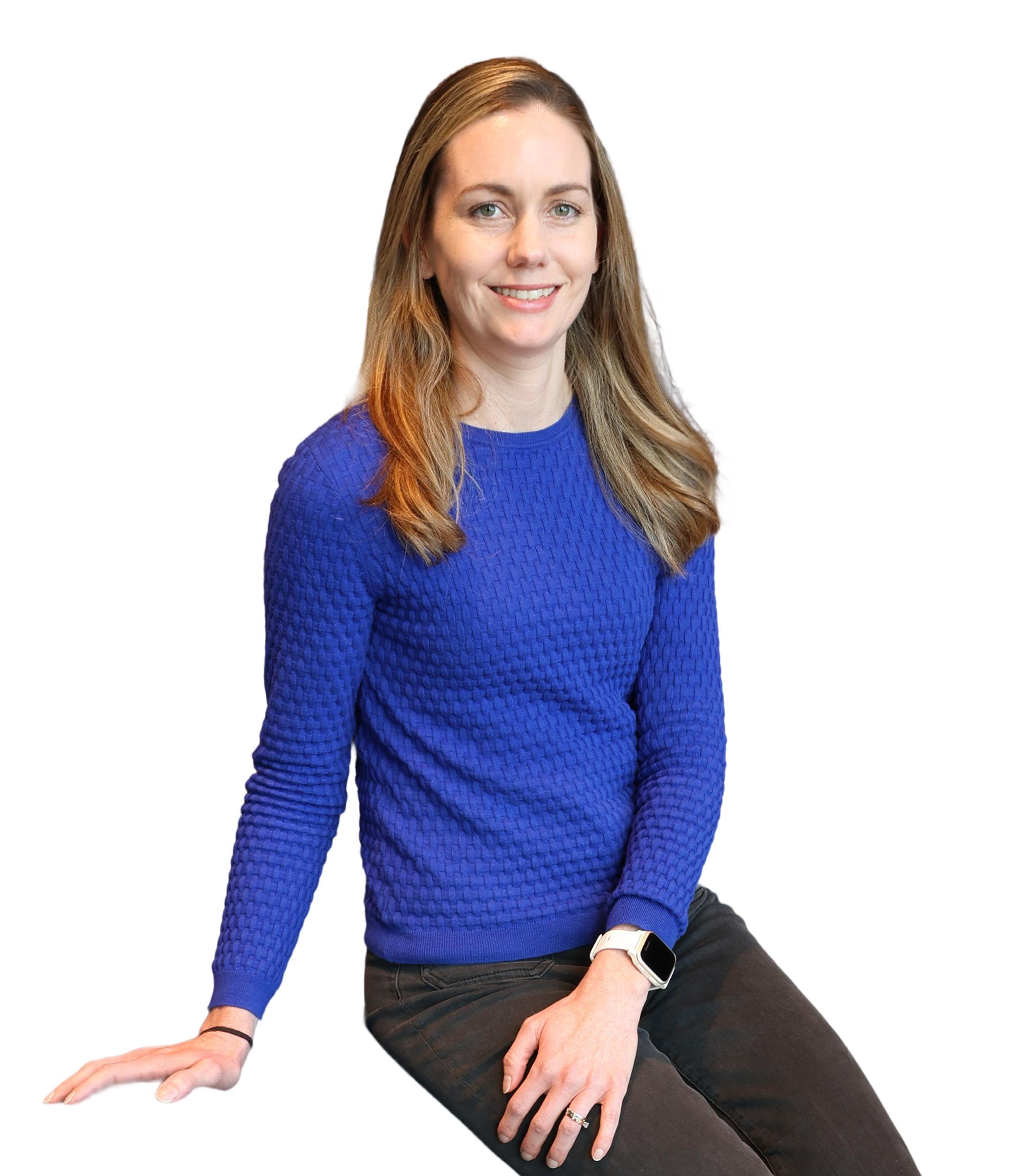 A woman with long, light brown hair, wearing a bright blue textured sweater, black pants, and a smartwatch, sitting against a black background, smiling at the camera.