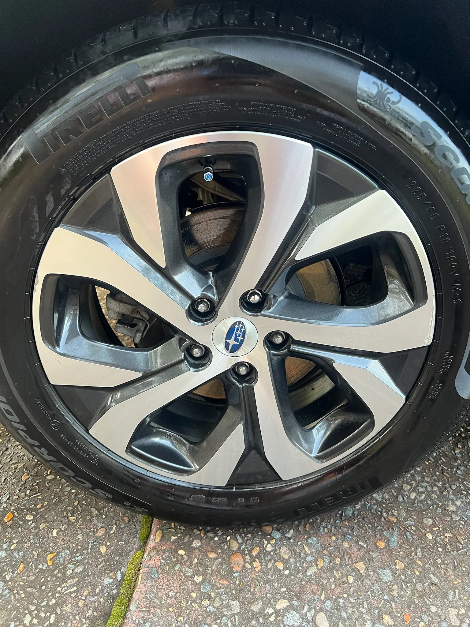 Close-up of a car wheel with a Subaru logo on the center cap. The wheel has a modern, multi-spoke alloy design and is fitted with a Pirelli tire.