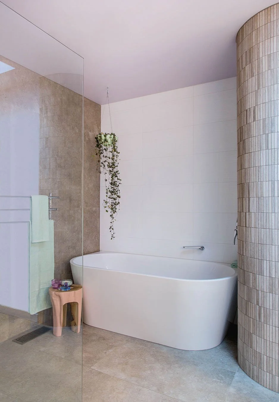 Modern bathroom with freestanding bath, curved tiled feature wall, walk-in shower and soft neutral finishes creating a calm, contemporary space