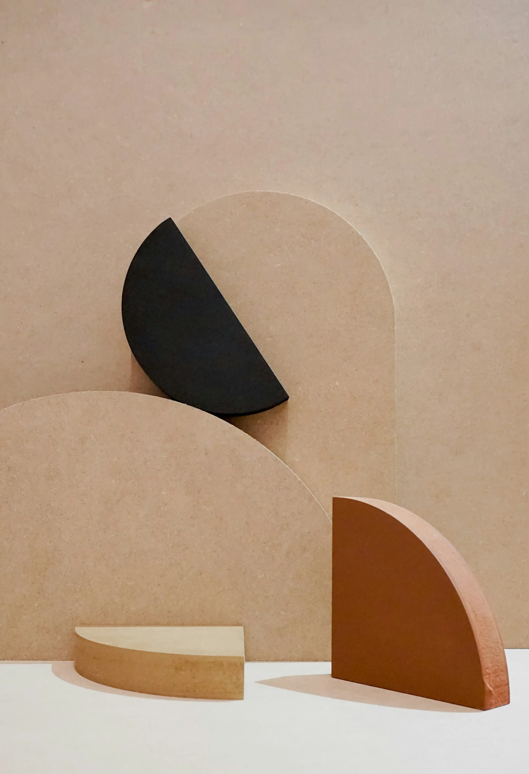 Abstract geometric wooden shapes, including semi-circles and quarter-circles, arranged on a neutral background.