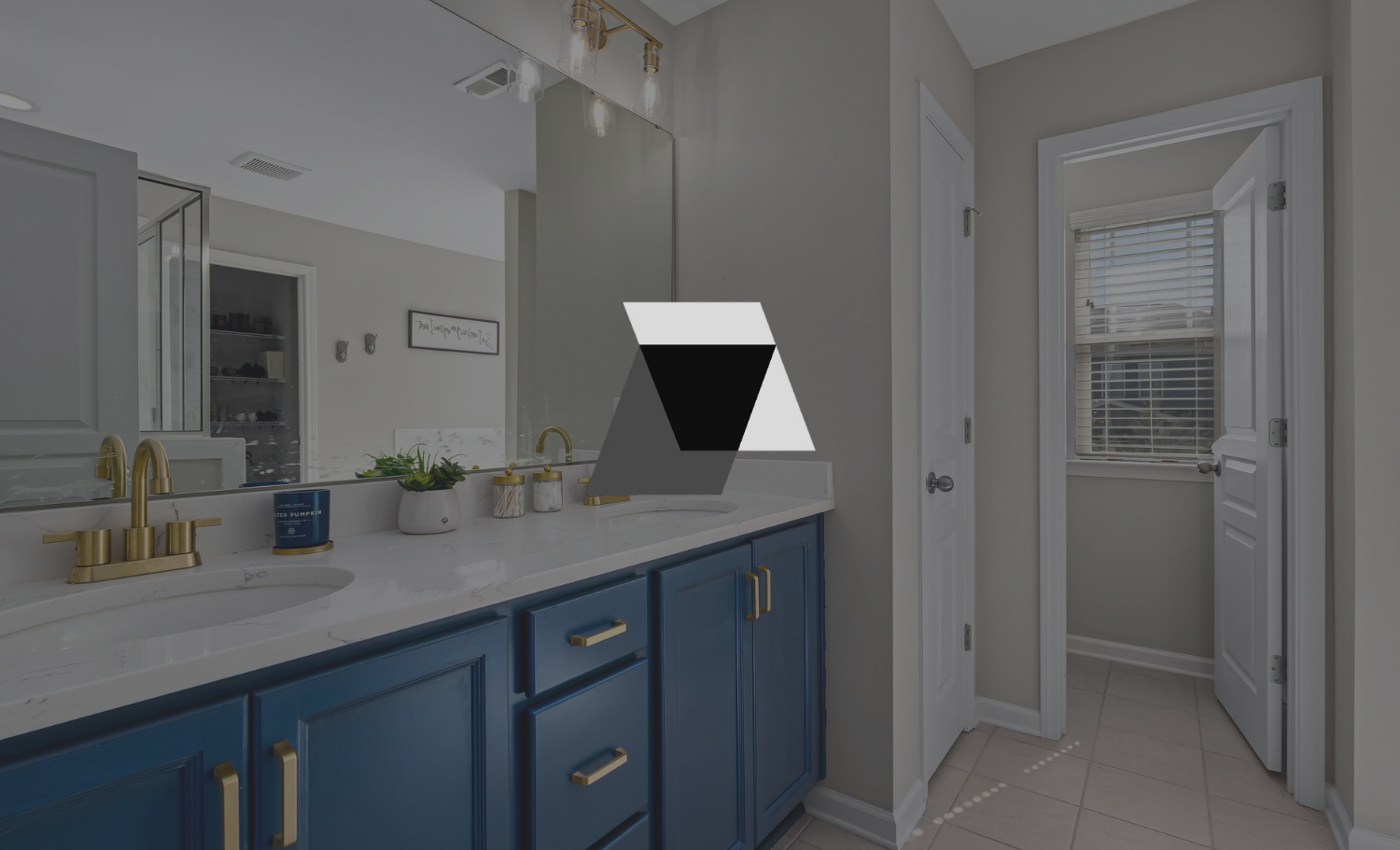 Modern bathroom with blue vanity, gold fixtures, marble countertop, large mirror, and window with blinds.