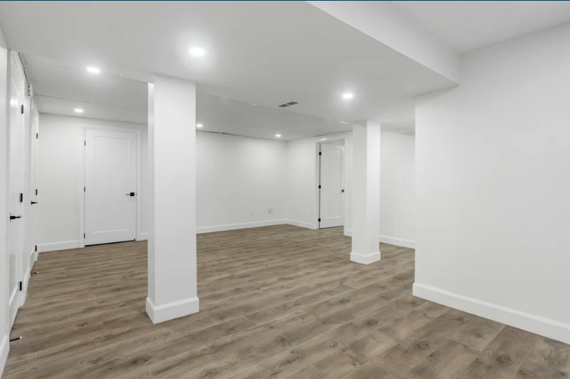 Interior home remodeling project showing finished basement with new flooring and recessed lighting