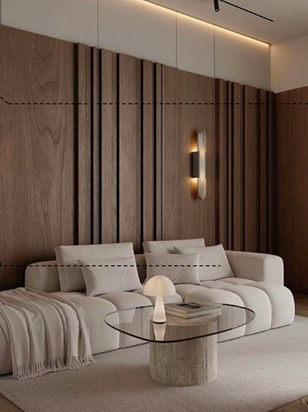 Modern living room with wooden panel wall, white sofa, glass coffee table, small lamp, and minimalist lighting.