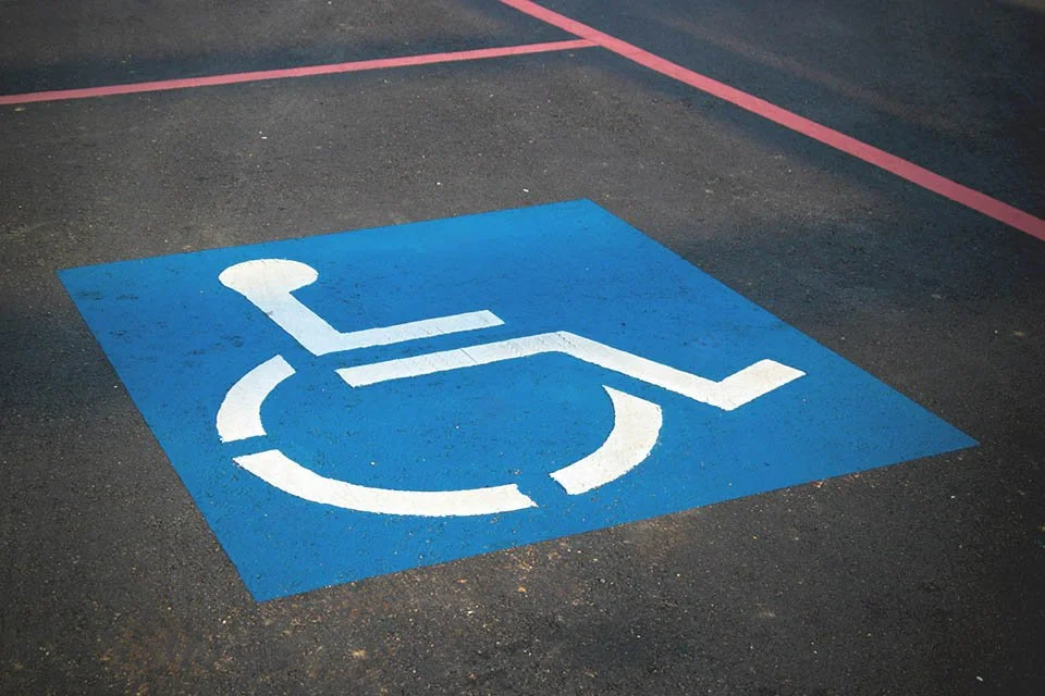 A disabled parking space marked with a blue square and a white wheelchair symbol painted on asphalt.