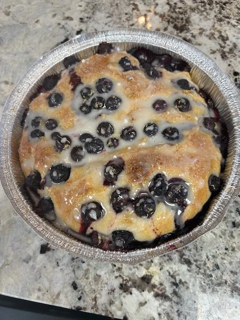 Mini blueberry cobbler in a foil container on a granite countertop.