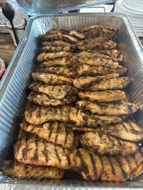 Grilled chicken wings arranged in a disposable aluminum tray with grill marks on some pieces.