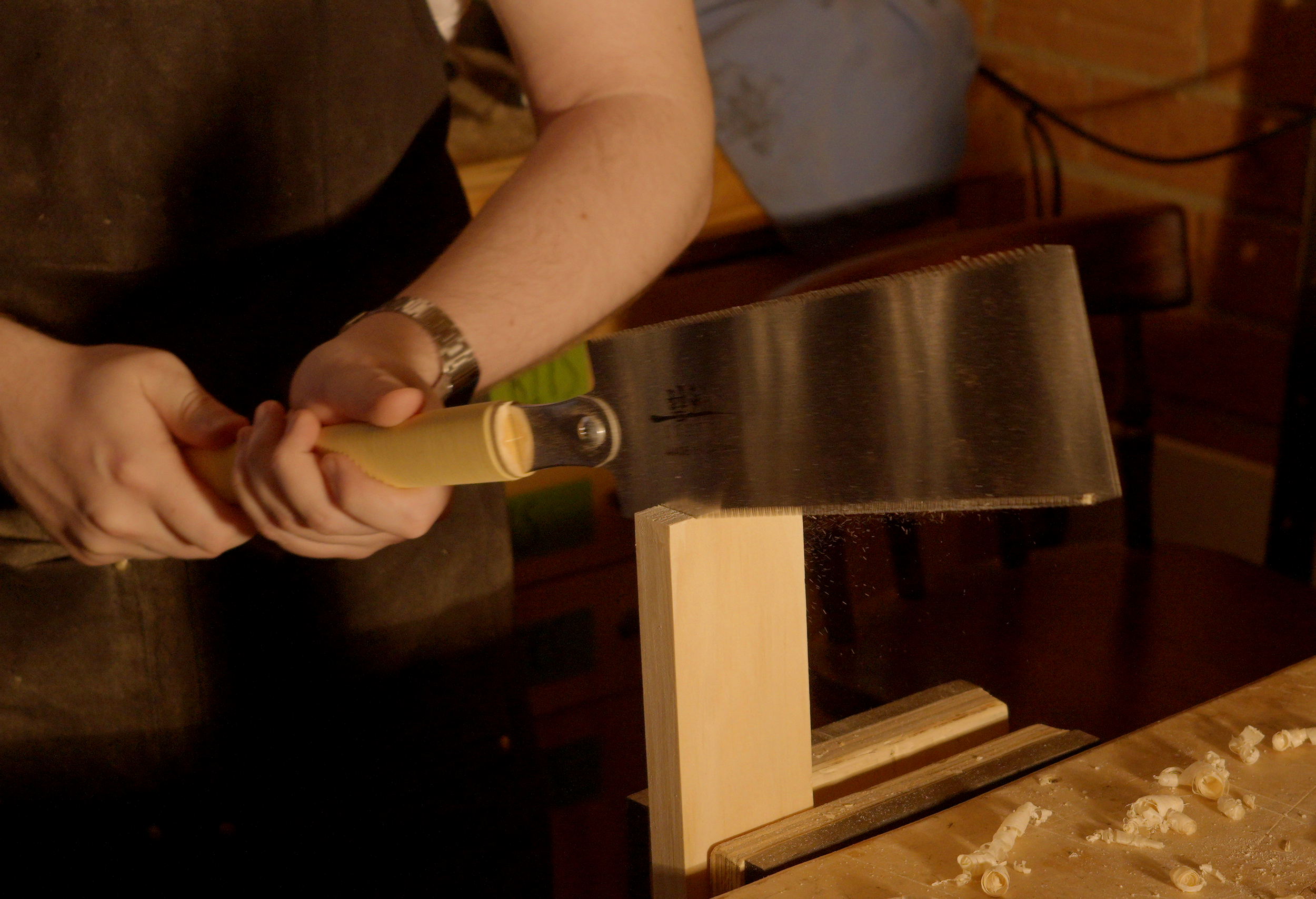 Person chopping wood with a hatchet in a woodworking setting