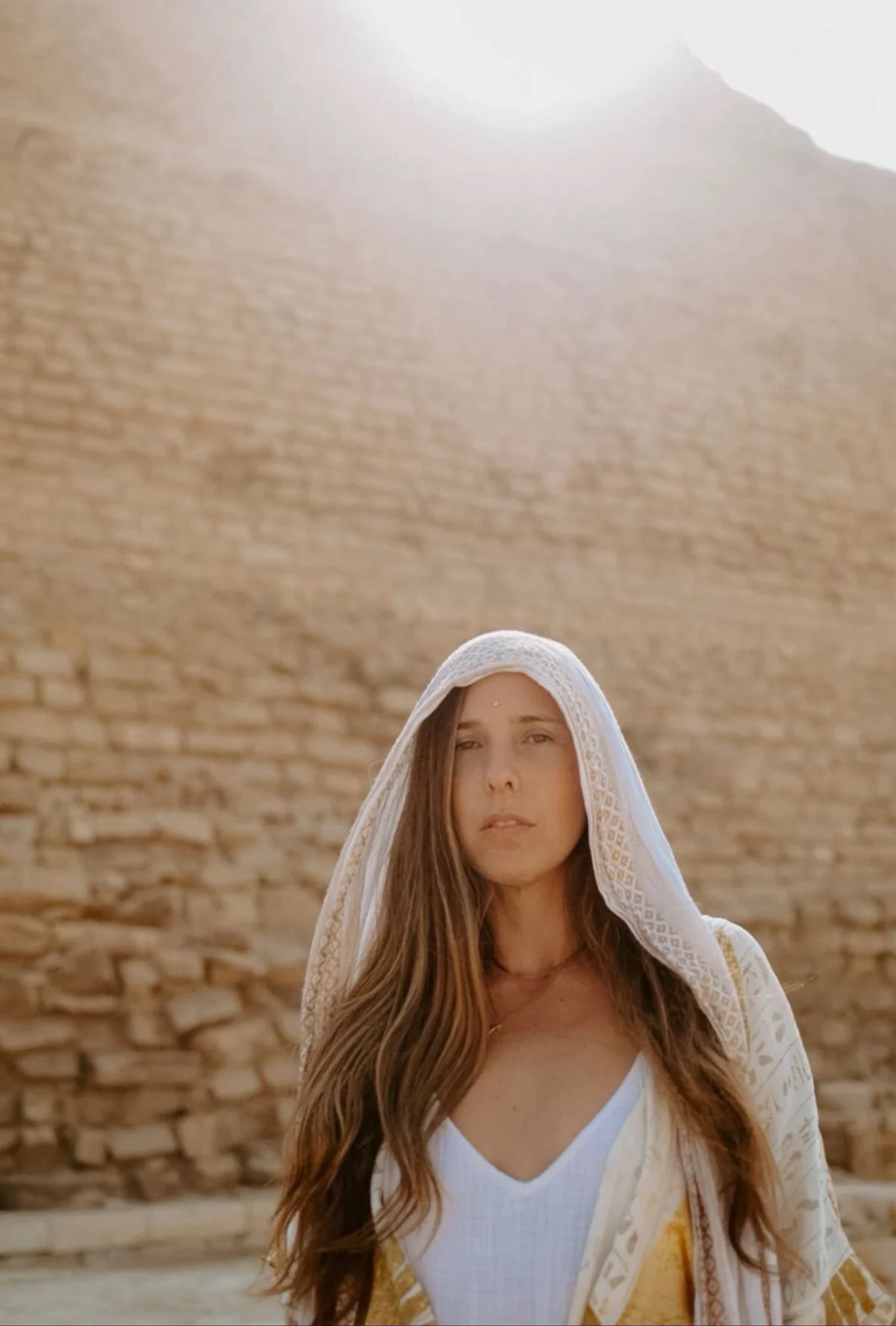 Iva Kelsey Phillips with white cloth covering head infront of ancient rock wall
