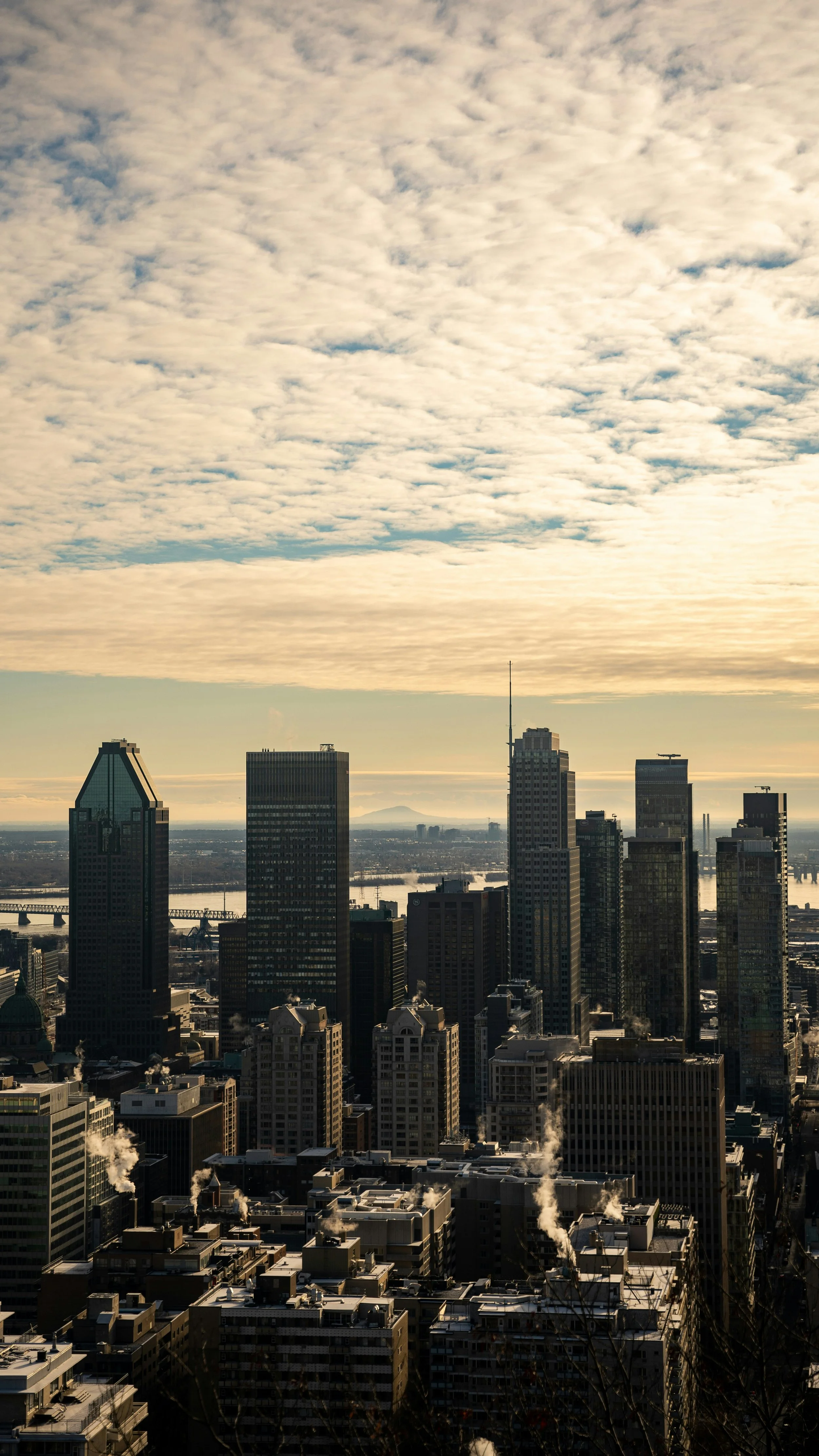 A city skyline with tall skyscrapers under a partly cloudy sky during sunset.