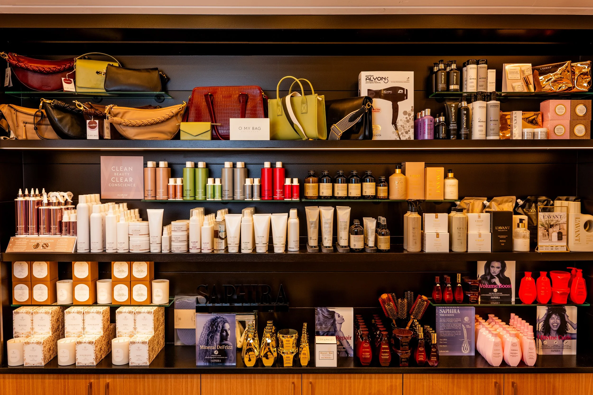 Shelves filled with handbags, skincare and haircare products, candles, and beauty items in a retail store.