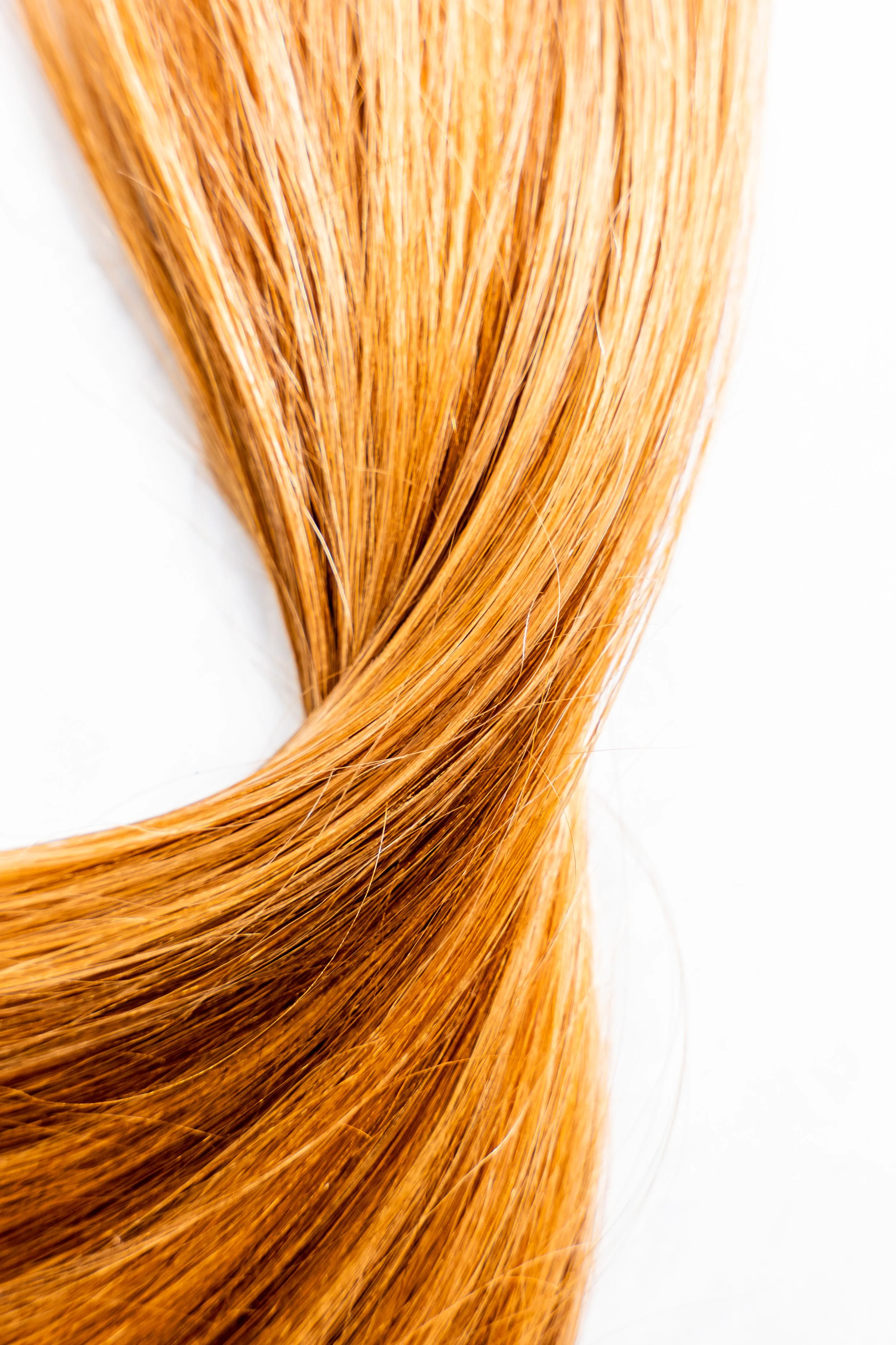 Close-up of straight, shiny, red hair against a white background.