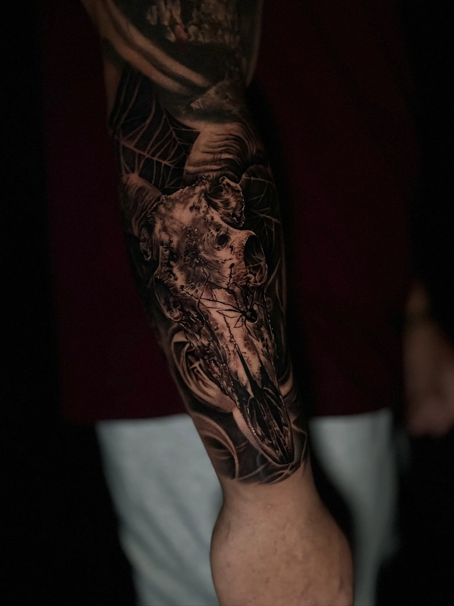 Tattoo of a wolf's skull on a person's arm, with geometric and abstract design elements surrounding it.