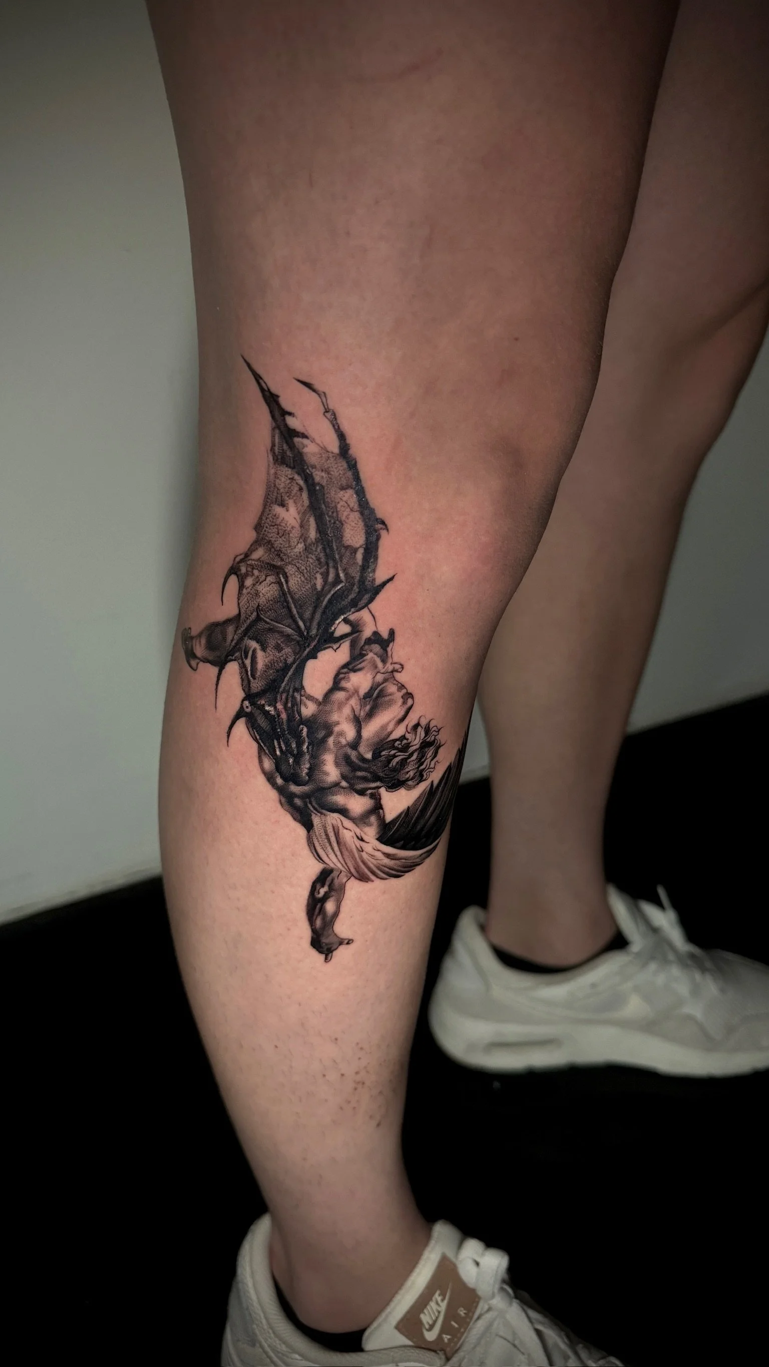 Black and gray tattoo of a woman with dragonfly wings on the thigh.