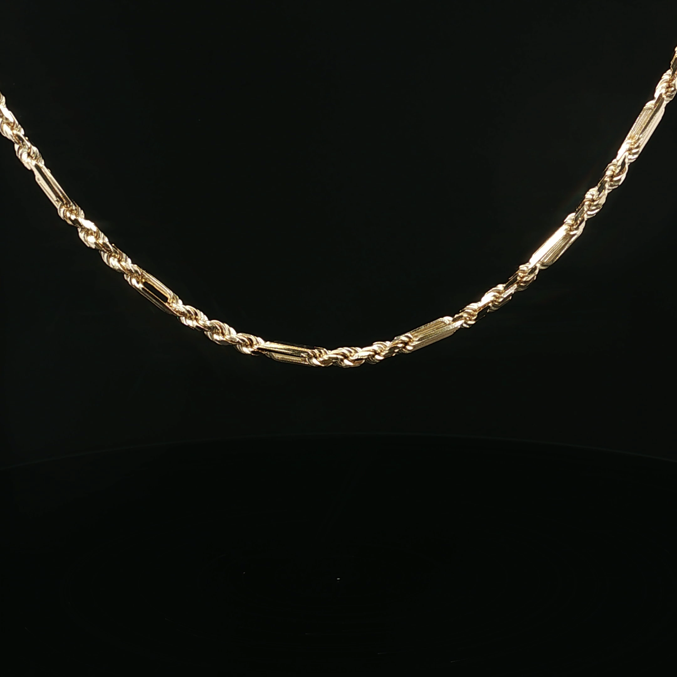 A gold chain necklace with a twisted rope design, set against a black background.