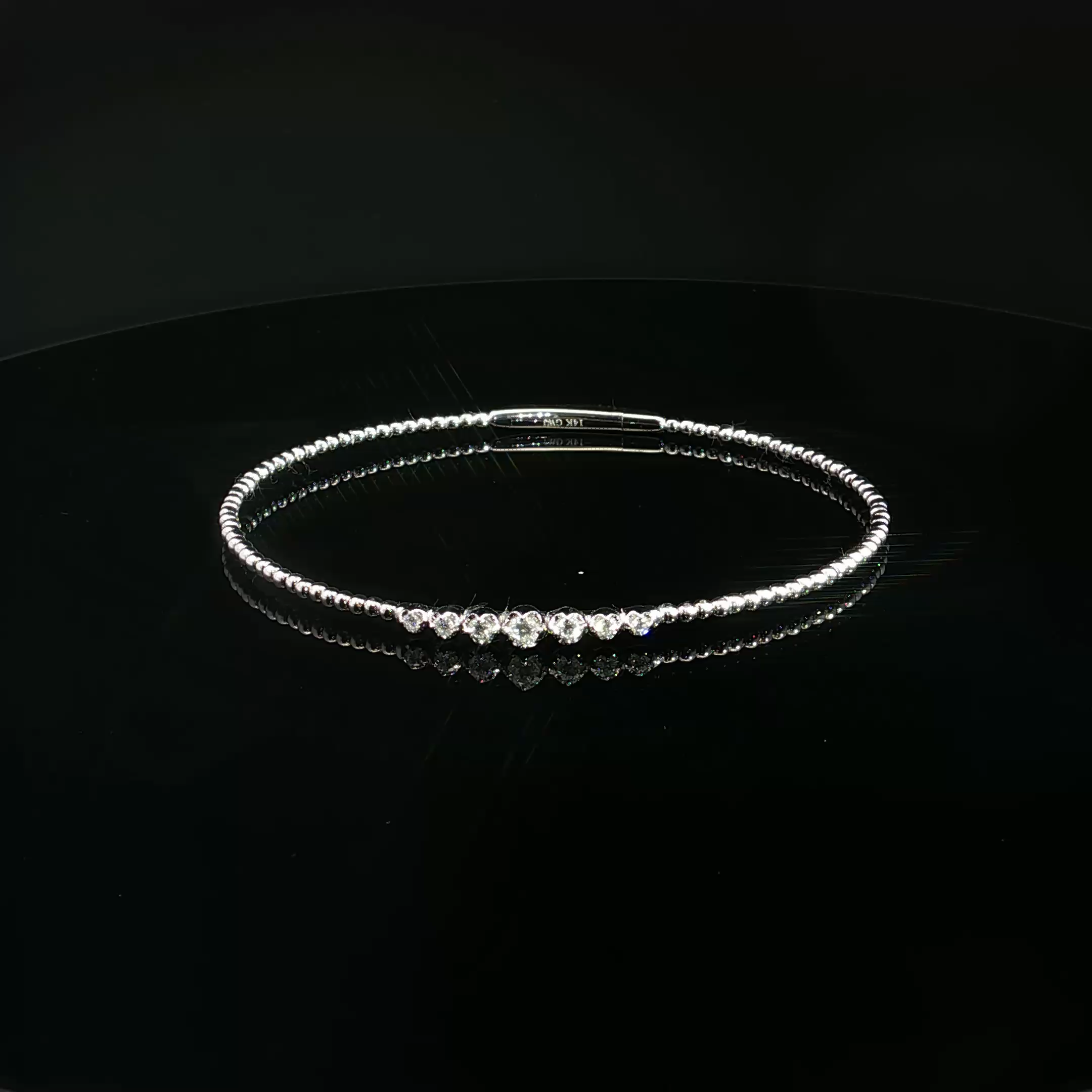Close-up of a sparkly diamond bracelet with multiple round-cut diamonds on a black background.