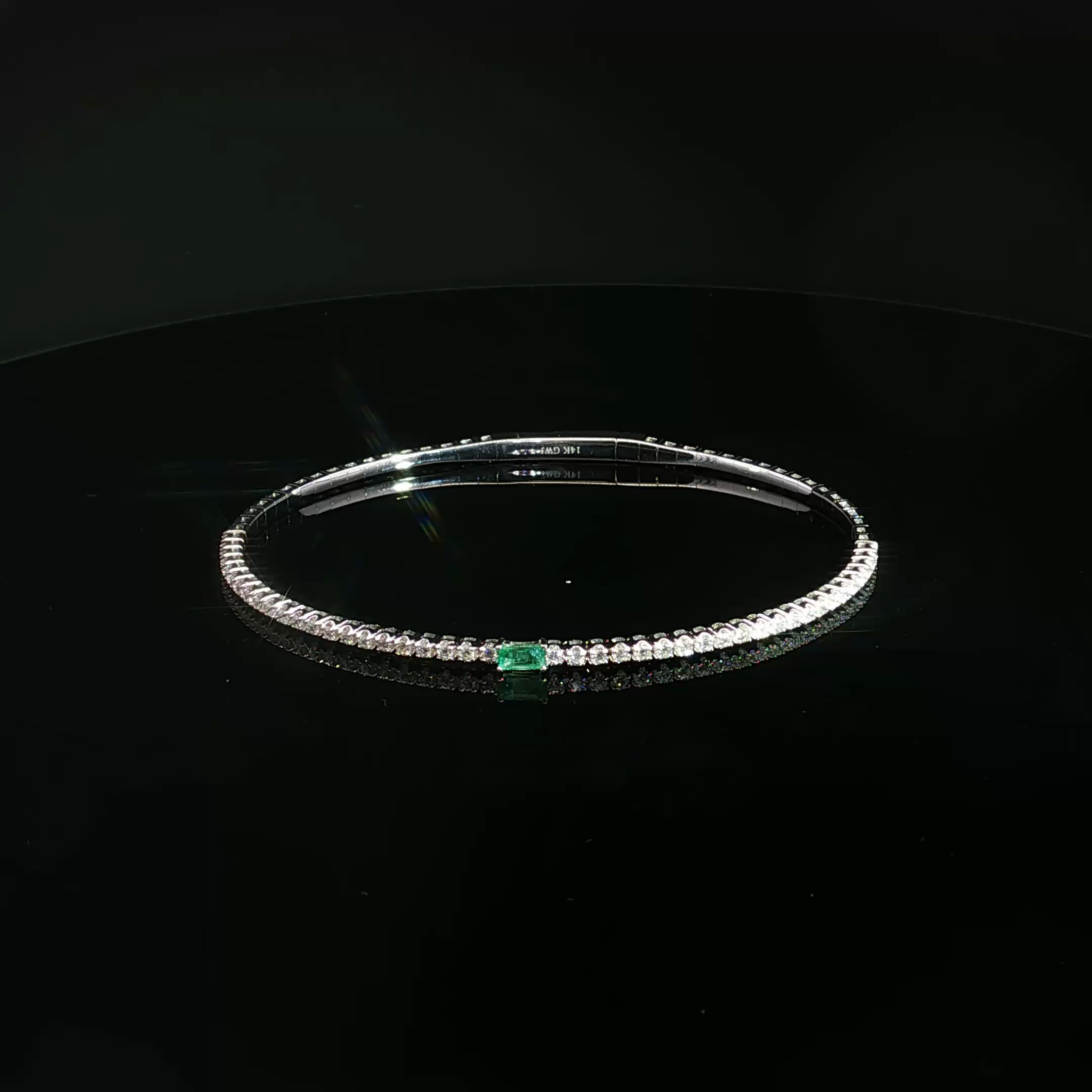 A close-up view of a diamond tennis bracelet with a clasp, displayed on a black surface.